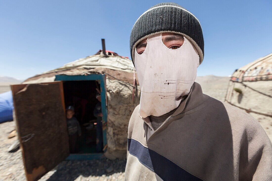 Tajikistan, Gorno-Badakhshan Autonomous Region, yurt camp by M41 road, also called Pamir Highway, portrait of a young Kyrgyz man wearing a mask on his face as a protection from the intense radiation of the sun, altitude 3900m