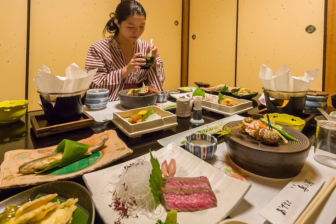 Japan, Kyushu Island, Kumamoto Region, Kurokawa Onsen, Ryokan Okunoyu, traditional luxury inn located in a spa town, young Asian woman in kimono enjoying traditional meal served in the room