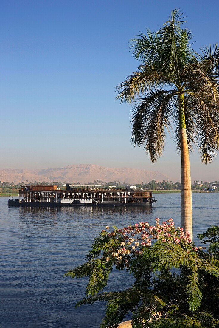 Ägypten,Oberägypten,Niltal,Dampfschiff Sudan,das letzte Dampfschiff auf dem Nil,das den Fluss von einem grünen Ufer aus überquert,mit den Bergen des Tals der Könige als Hintergrund