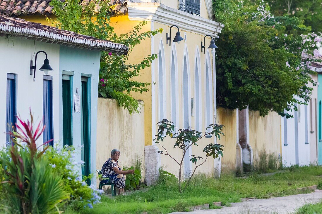 Brazil, state of Bahia, Porto Seguro, Historic City, where Pedro Alvares Cabral created the first Portuguese settlement in Brazil in 1500, elderly woman sitting in front of a row of historic houses