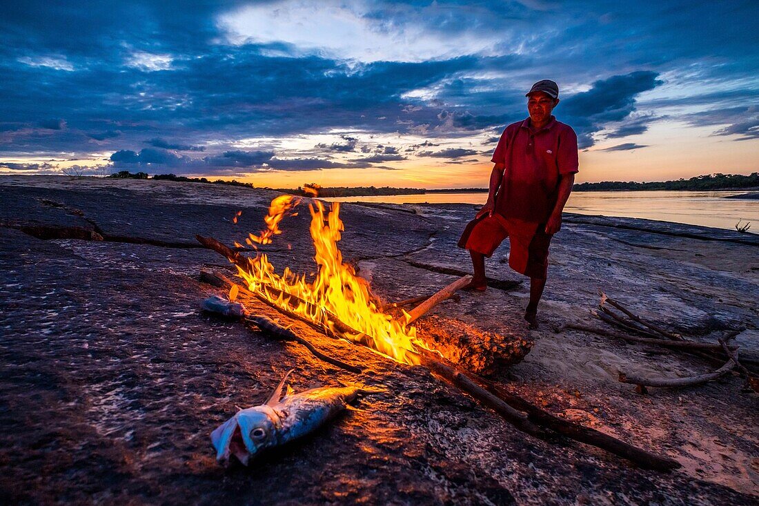 Colombia, Llanos, Vichada, Tambora, Tuparro National Park, fisherman grilling a catch on his fire