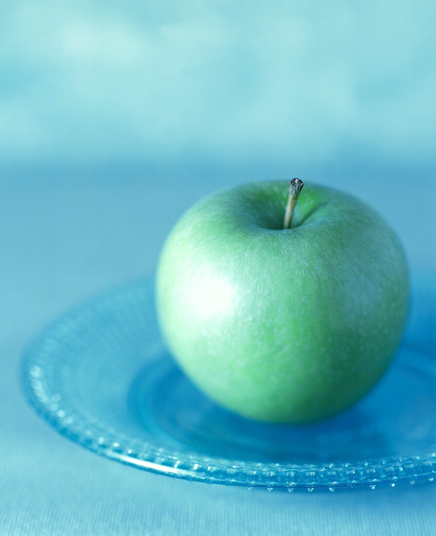 Grüner Apfel (Granny Smith) auf blauem Glasteller