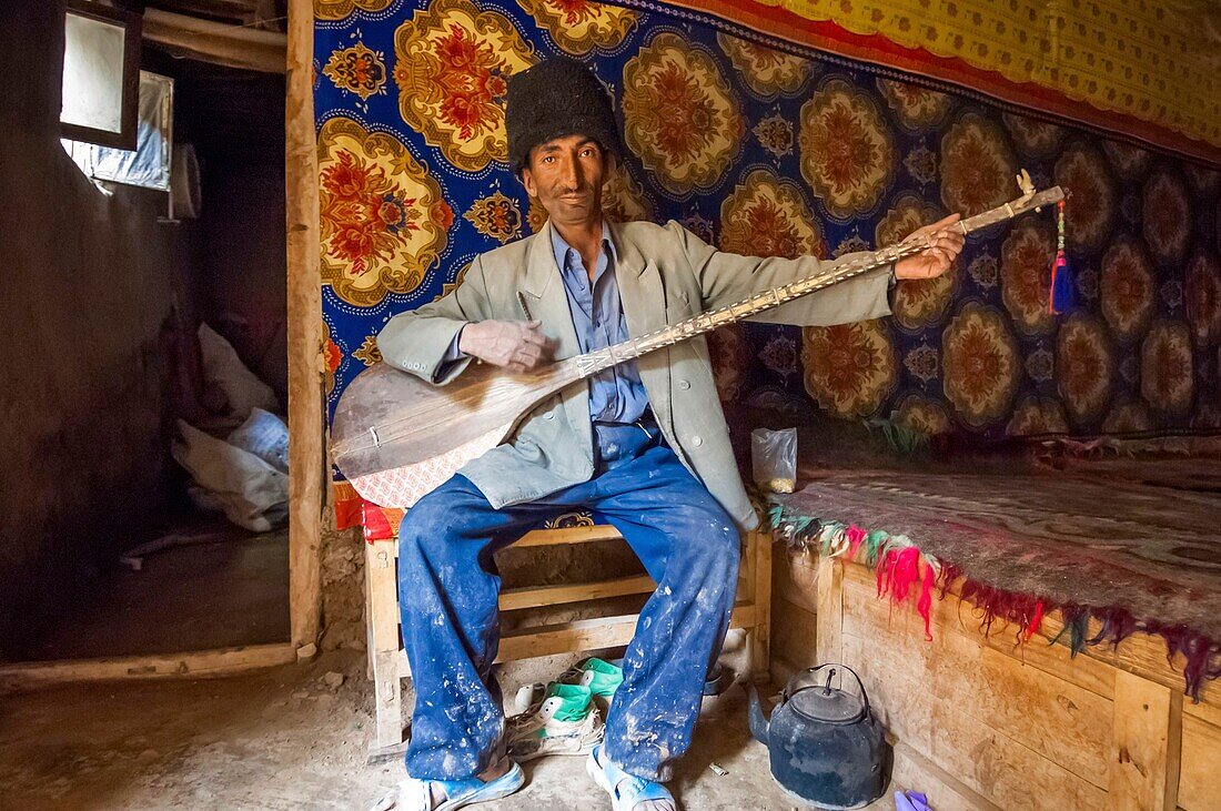 China, Xinjiang autonomous region, Sanju, shepherd with astrakan hat playing the dôtar, or traditional luth