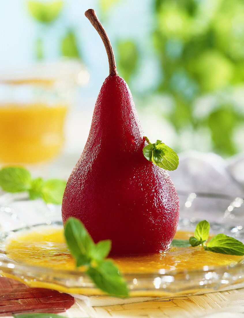 Red wine pear with apricot sauce on glass plate