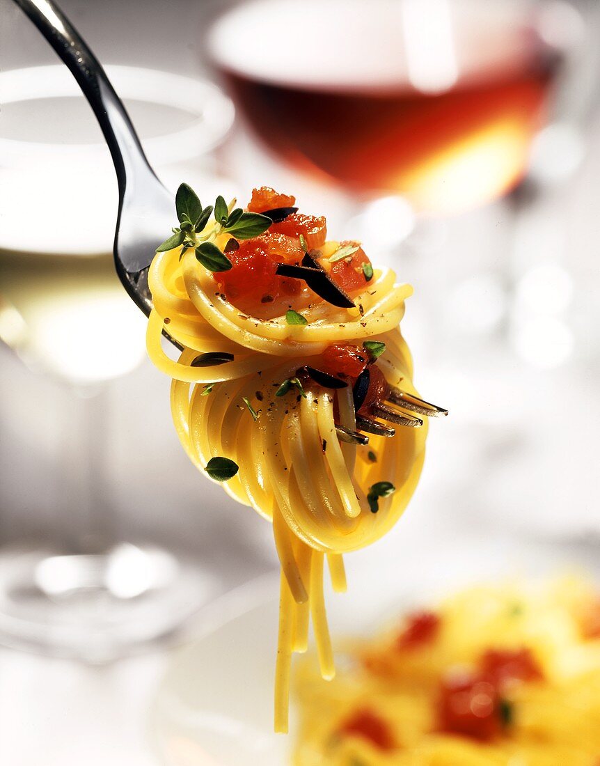 Spaghetti mit Tomaten-Oliven-Sauce auf Gabel