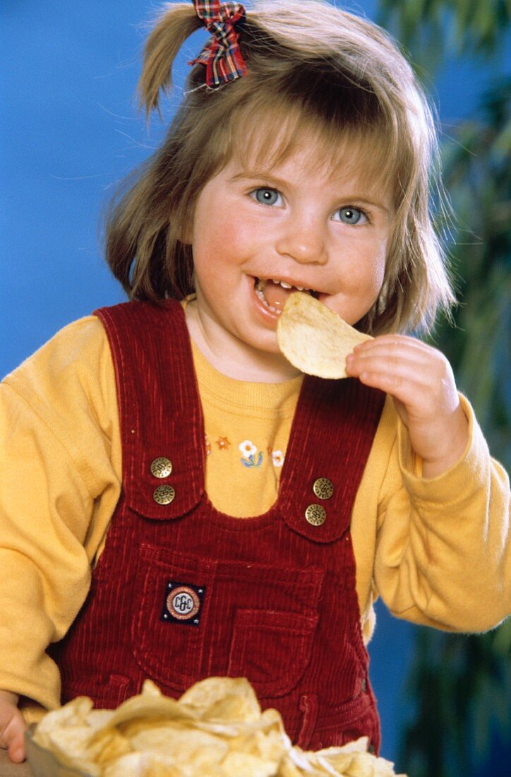 Kleines Mädchen isst Kartoffelchips