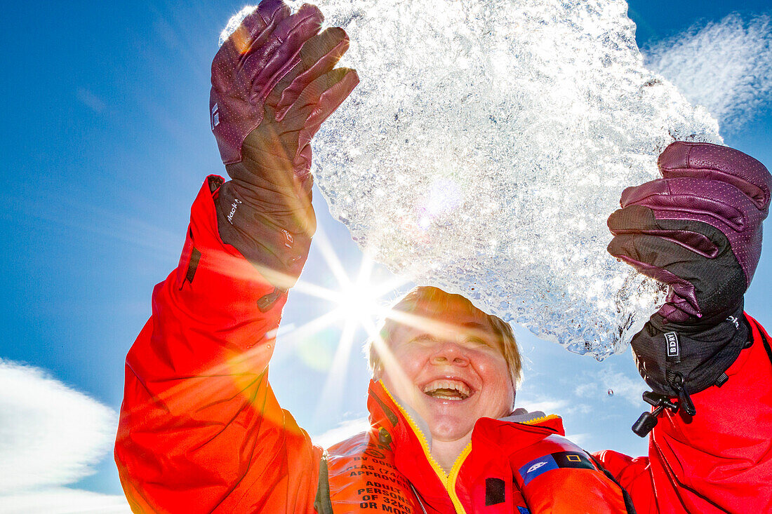 Guest from the Lindblad Expedition ship National Geographic Explorer holding up a block of ice in the Svalbard Archipelago, Norway, Arctic, Europe