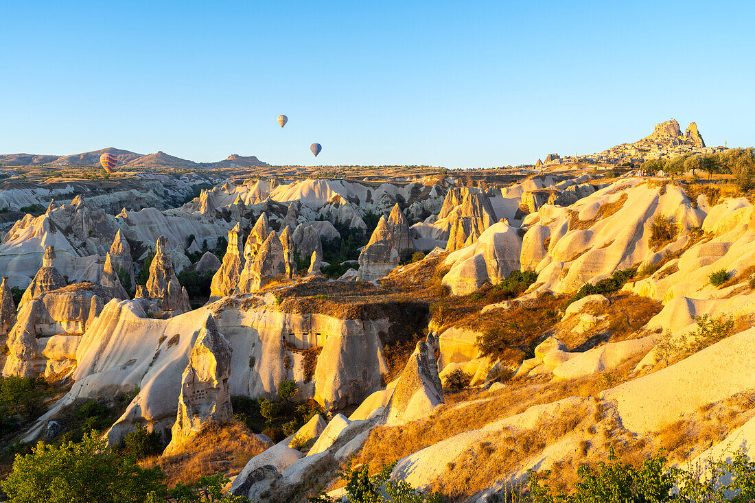 Rock formations with distant views of Uchisar Castle at sunrise, Goreme, Cappadocia, Anatolia, Turkey, Asia Minor, Asia