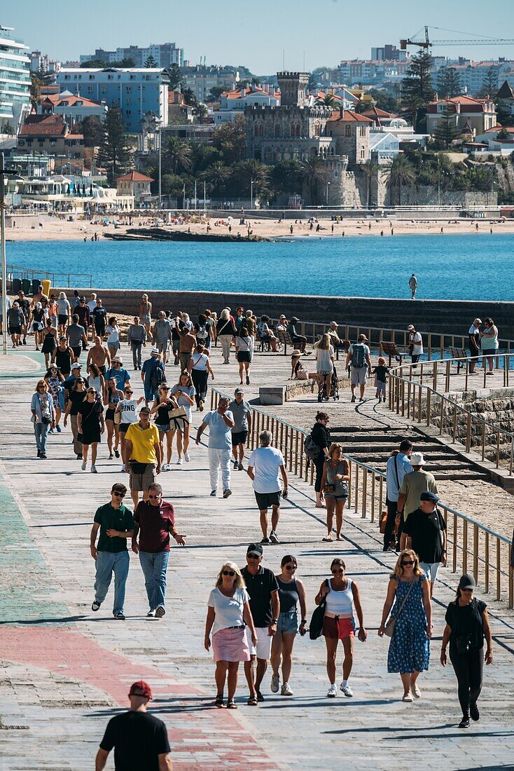 Menschen schlendern an einem warmen Herbsttag über die Uferpromenade zwischen Cascais und Estoril,Portugal,Europa