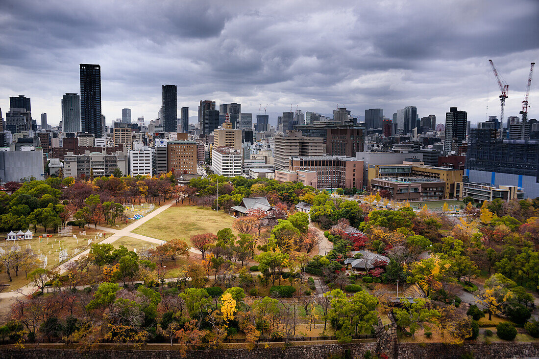 Blick über den Schlosspark auf die Skyline der Stadt mit dramatischem Himmel im Herbst,Osaka,Honshu,Japan,Asien