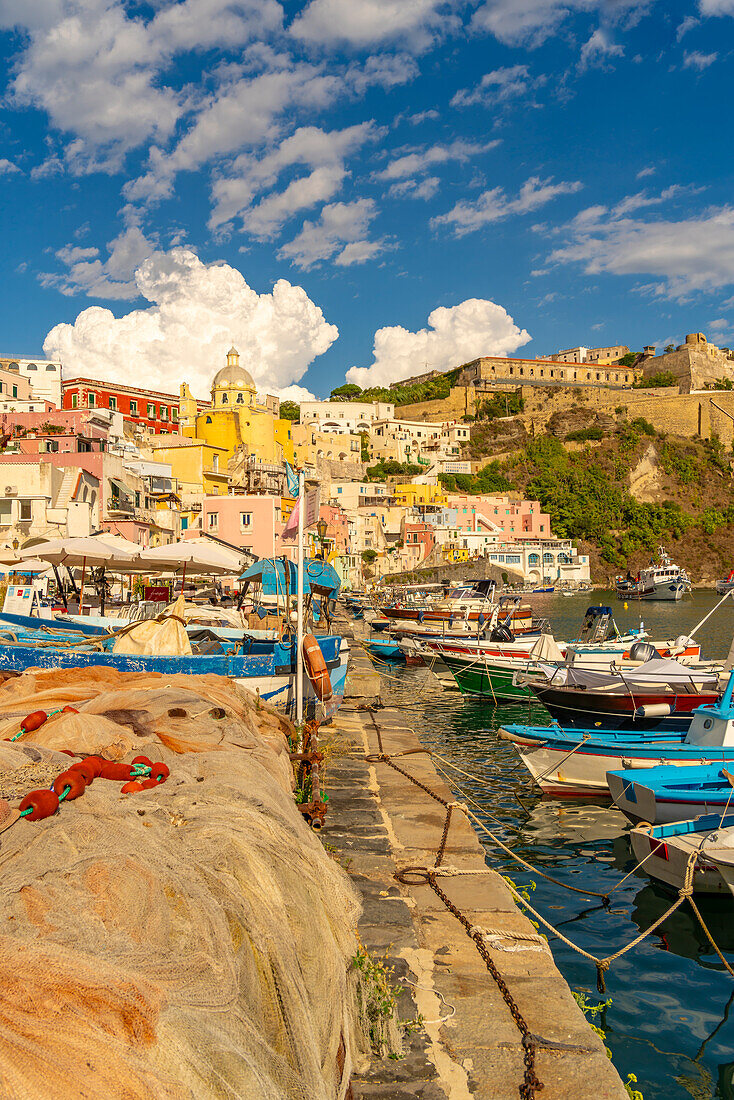 Blick auf Fischernetze und Boote in Marina di Corricella und die Kirche Santa Maria delle Grazie im Hintergrund,Procida,Phlegräische Inseln,Golf von Neapel,Kampanien,Süditalien,Italien,Europa