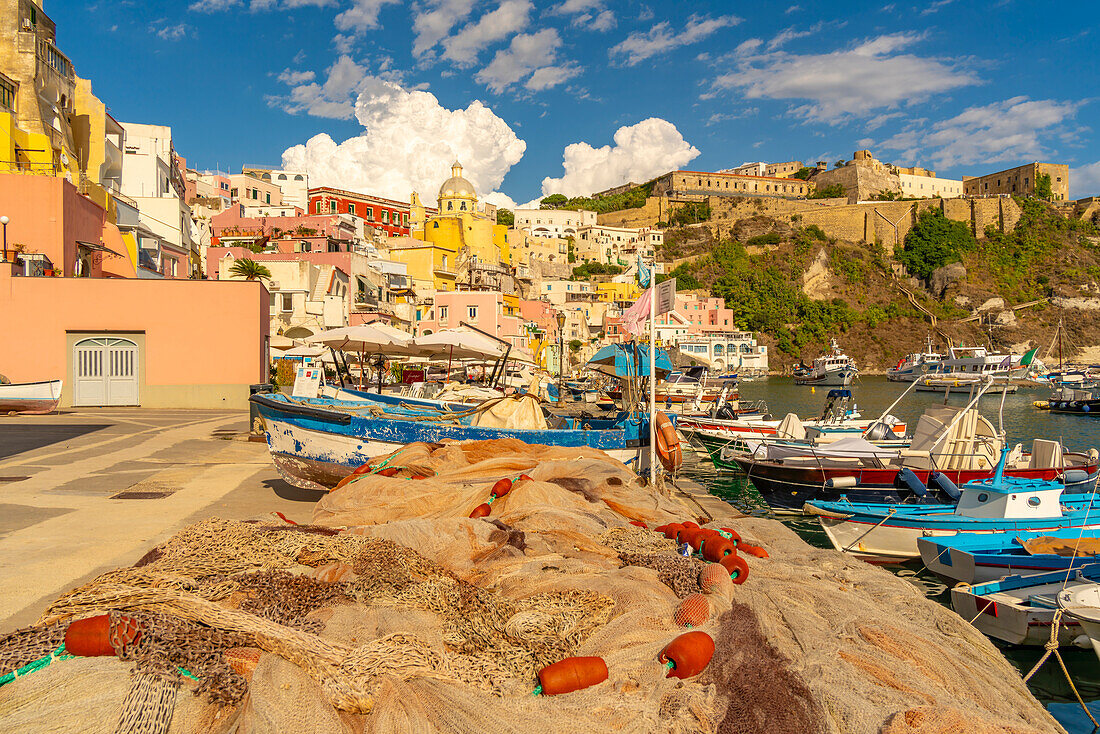 Blick auf Fischernetze und Boote in Marina di Corricella und die Kirche Santa Maria delle Grazie im Hintergrund,Procida,Phlegräische Inseln,Golf von Neapel,Kampanien,Süditalien,Italien,Europa