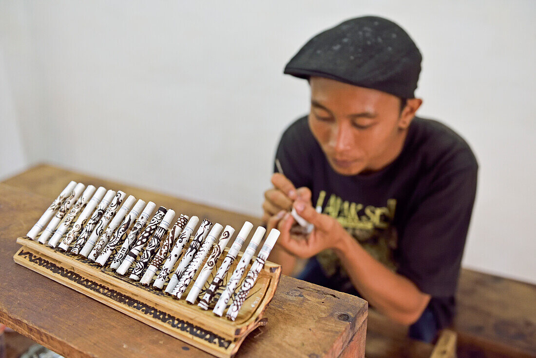 Mann malt Batikmuster mit Kaffeesatz auf Zigaretten,Tapel Koeda Kretek (Nelkenzigaretten) Fabrik in Juwana,Insel Java,Indonesien,Südostasien,Asien