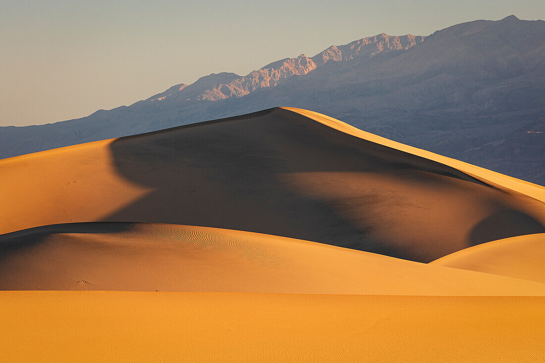 Warmes Licht des Sonnenaufgangs umhüllt die Sanddünen bei Mesquite Flat,Death Valley,Kalifornien,Vereinigte Staaten von Amerika,Nordamerika