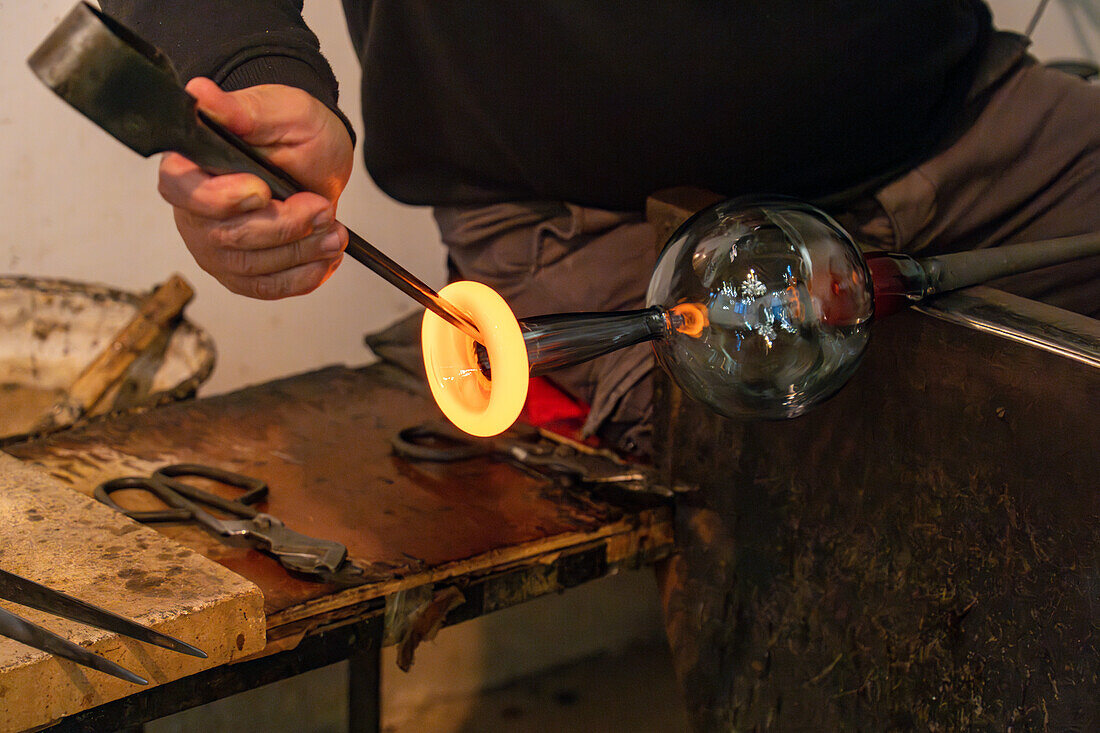 The glassblower shapes a spout for the pitcher with jacks in a glassblowing demonstration in Venice, Italy.