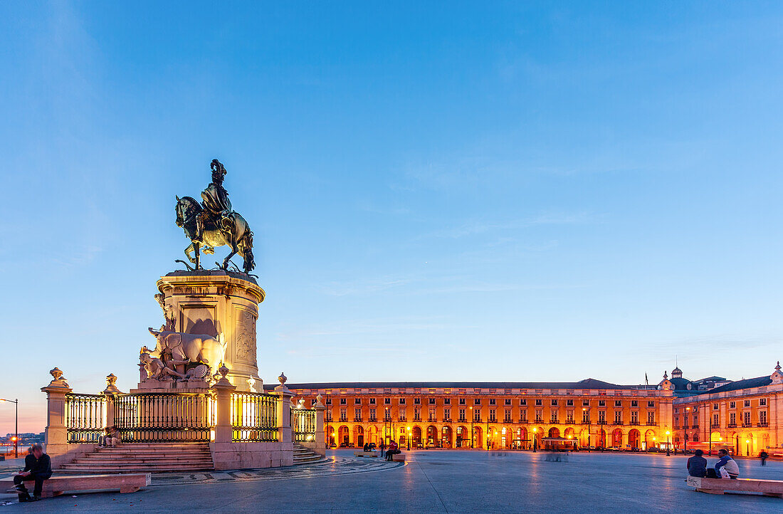 In der Abenddämmerung ist auf dem Praça do Comércio in Lissabon die beleuchtete Statue von Dom José I. zu sehen,die eine lebendige Stadtatmosphäre schafft.