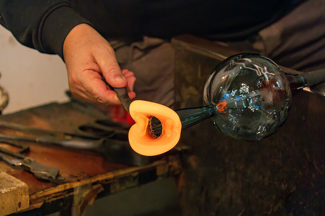 The glassblower shapes a spout for the pitcher with jacks in a glassblowing demonstration in Venice, Italy.