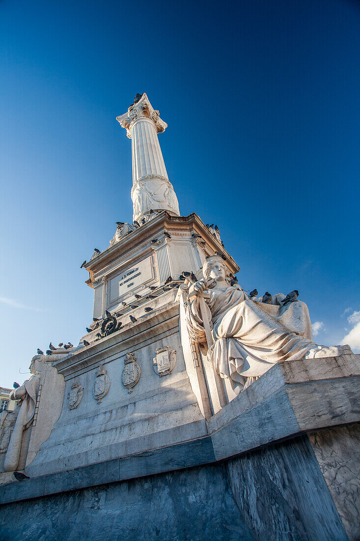 The impressive monument of King Dom Pedro IV stands tall in Rossio Square, surrounded by charming architecture and a vibrant atmosphere.