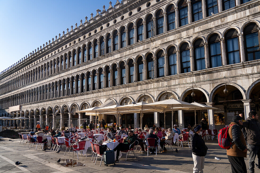 People dining al fresco in front of the Procuratie Vecchie in St. Mark's Square in Venice, Italy.