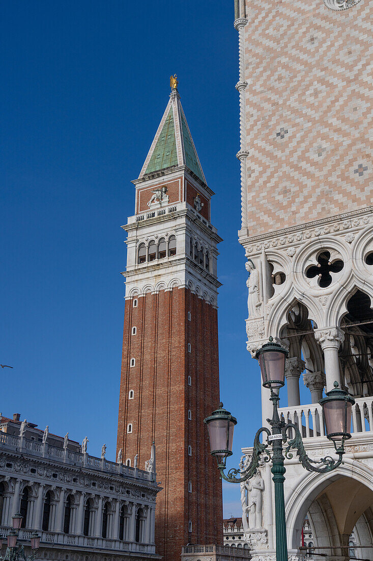 The campanile or bell tower of the Patriarchal Cathedral Basilica of Saint Mark or St. Mark's Basilica in Venice, Italy. At left is the Marciana National Library. At right is the Doge's Palace.