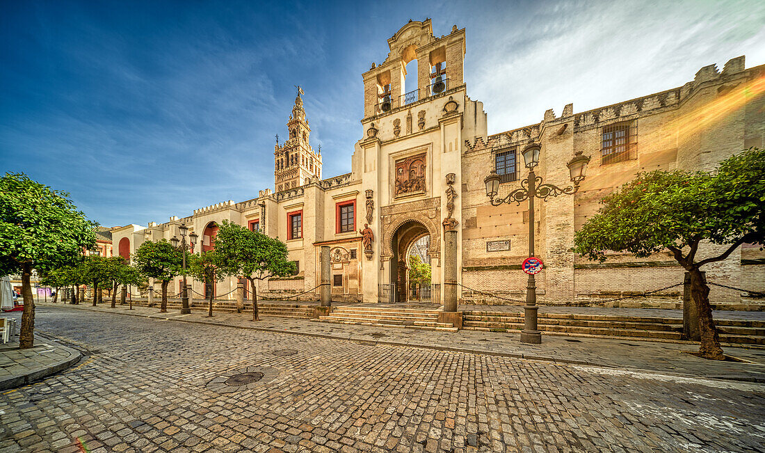 Captivating view of Puerta del Perdon and the iconic Giralda tower in Seville, Spain. The image showcases stunning historical architecture with a clear blue sky background.