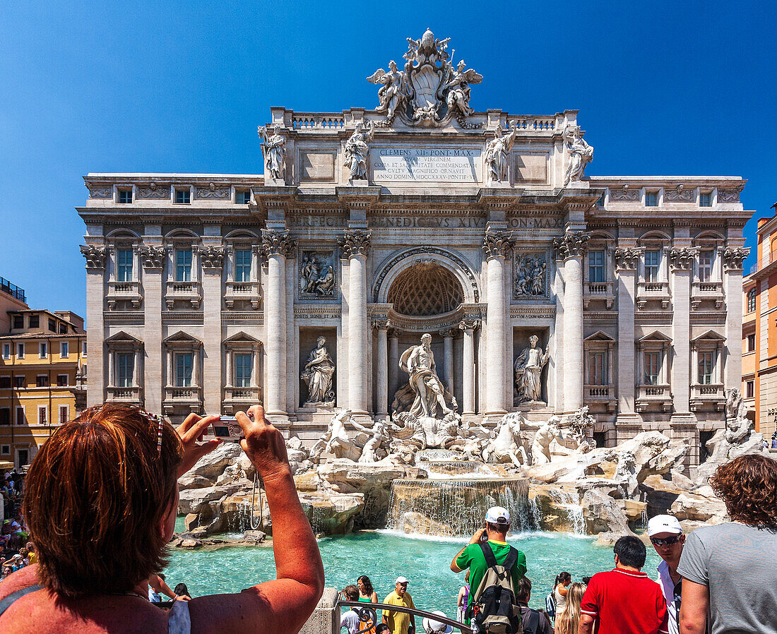 Rome, Italy, July 22 2017, Tourists enthusiastically take pictures of the stunning Trevi Fountain in Rome, enjoying the vibrant atmosphere under a clear blue sky.