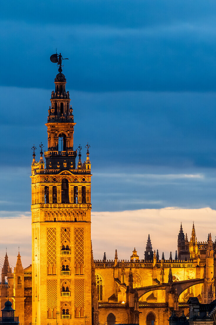 Stunning aerial view of the iconic Giralda Tower in Seville, Spain, beautifully illuminated at dusk. Captures the historic charm and architectural majesty of this famous landmark.