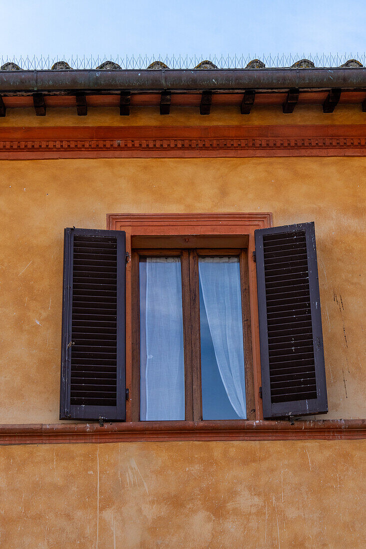 Wooden shutters on a building in the medieval walled town of Monteriggioni, Sienna, Tuscany, Italy.