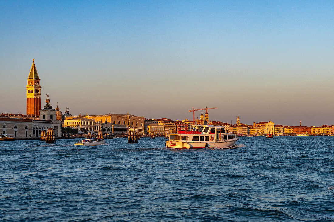 Buildings along the waterfront of the Giudecca Canal at sunset in Venice, Italy. The campanile or bell tower of the Basilica of St. Mark is at left.