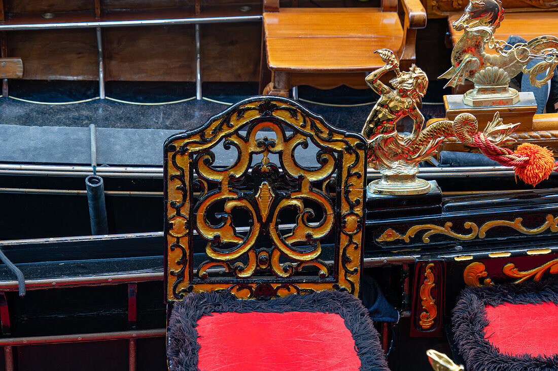 Detail of a gondola in Venice, Italy, showing a painted chair and brass merman.