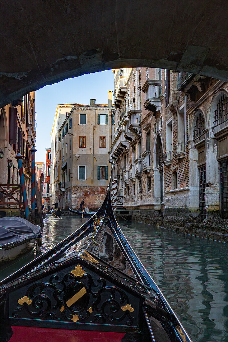 A gondola passes under a stone bridge over a canal in Venice, Italy.