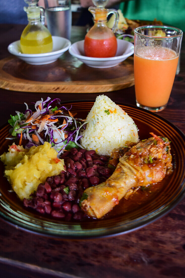 Casado dish with rice, chicken and peas, and fruit juice on table.