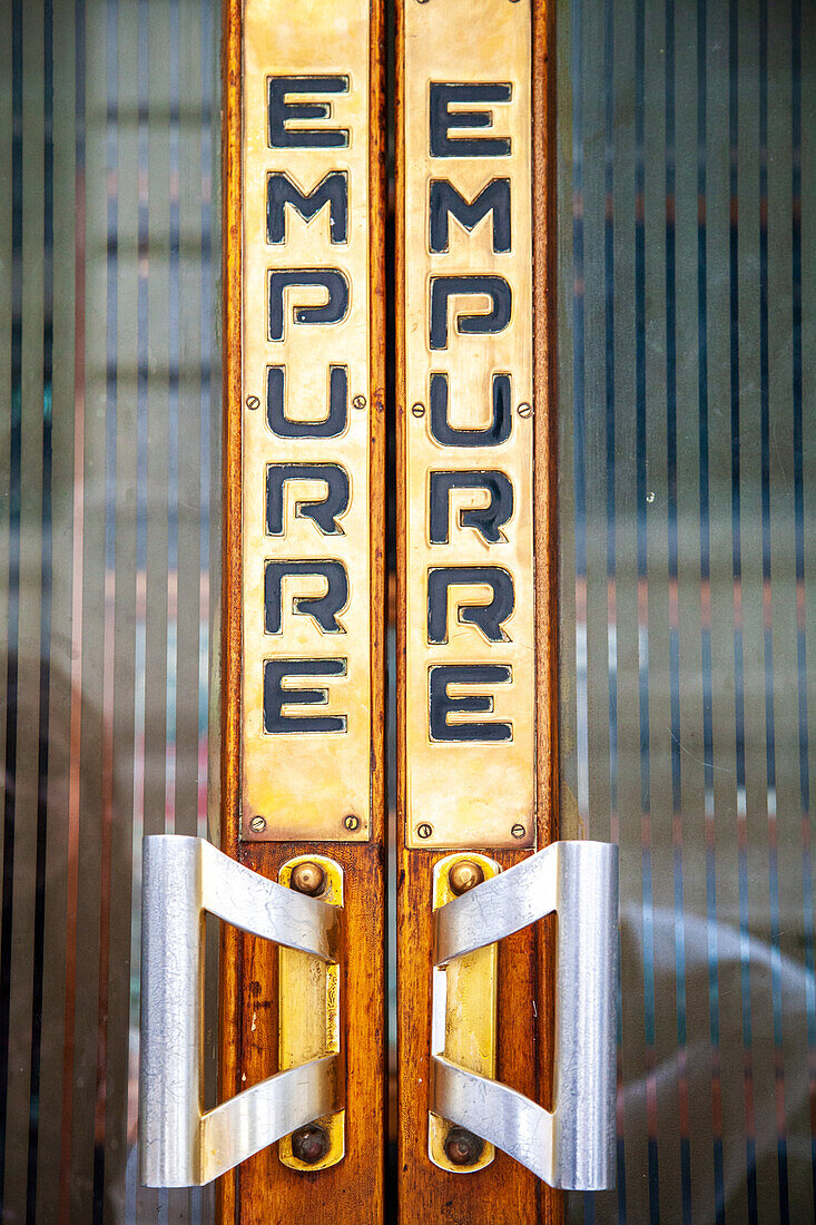 A detailed close up of a vintage door handle with the word 'Empurre' in Lisbon, Portugal. The wooden and metallic textures add an antique charm.