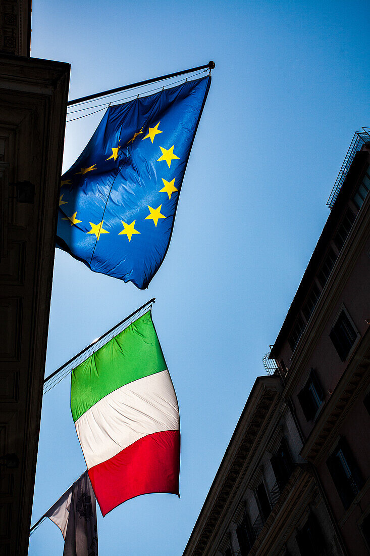 The vibrant flags of Italy and the European Union fly high against a clear blue sky in Rome, capturing the essence of the city.