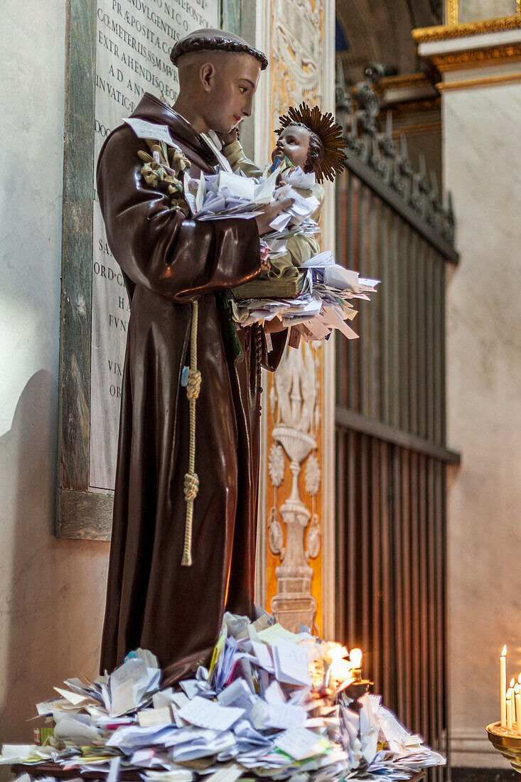 Rome, Italy, July 2017, Worshippers leave expressions of faith and gratitude at the Sant Antonio statue in a historic Roman church, filling it with notes.