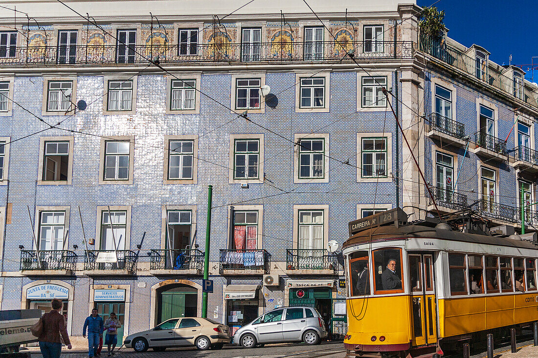 Lisbon, Portugal, March 1 2007, A vibrant yellow tram travels along Rua Augusto Rossa, showcasing glazed ceramic tile architecture in Lisbon, Portugal.