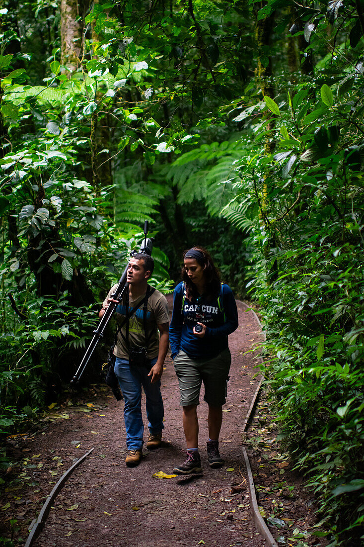 George of the Cloud Forest, guide and specialist, guides a young woman through Monterey cloud forest during fauna tour, Costa Rica