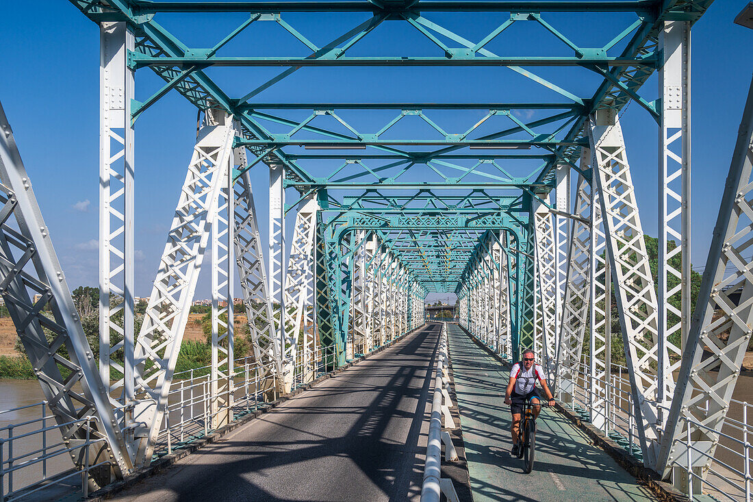 Sevilla,Spanien,17. September 2024,Ein Radfahrer fährt auf dem Radweg der 1930 erbauten Eisenbrücke San Juan über den Fluss Guadalquivir in Sevilla,Spanien. Das Bauwerk zeichnet sich durch eine komplizierte Stahlarchitektur aus.