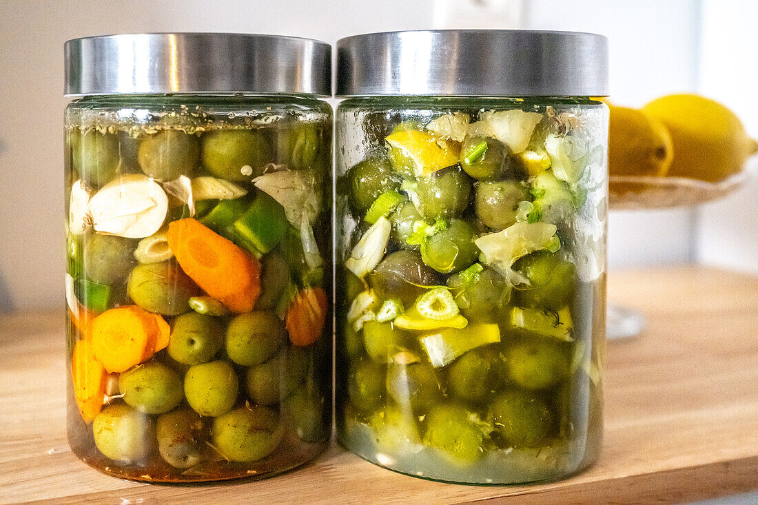 Two jars of traditional Andalusian-style pickled olives made at home, showcasing vibrant colors and fresh ingredients from Seville. Perfect representation of Mediterranean culinary heritage.