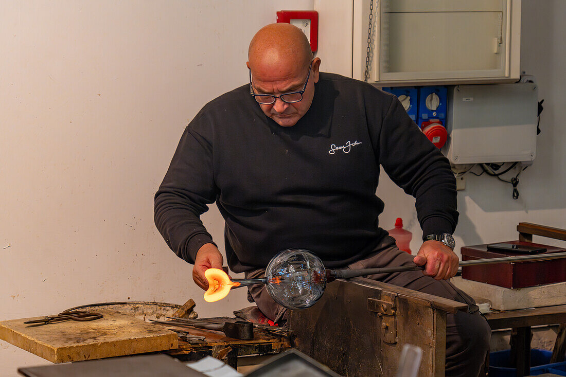 The glassblower shapes a spout for the pitcher with jacks in a glassblowing demonstration in Venice, Italy.