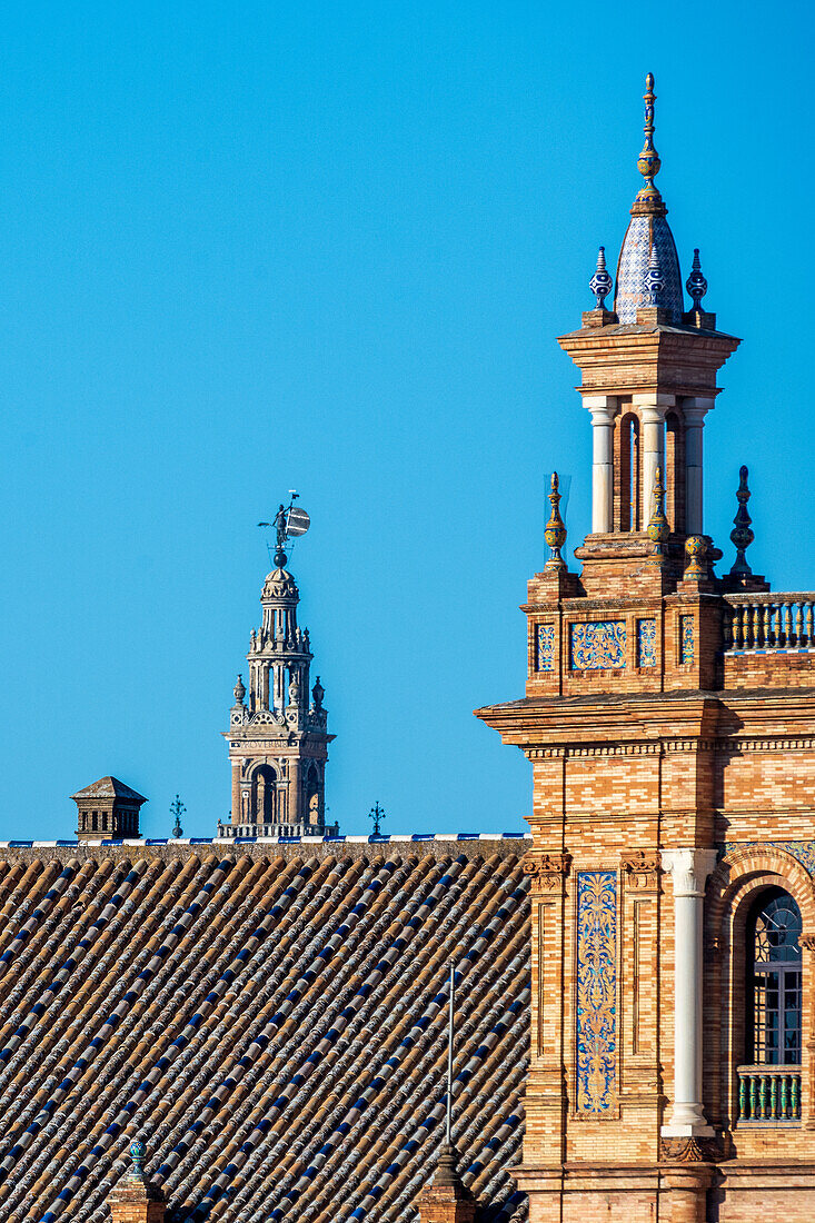 A stunning portrayal of the architectural grandeur of Plaza de España in Seville, Spain, featuring intricate brickwork and the historic Giralda tower gracing the background against a clear blue sky.