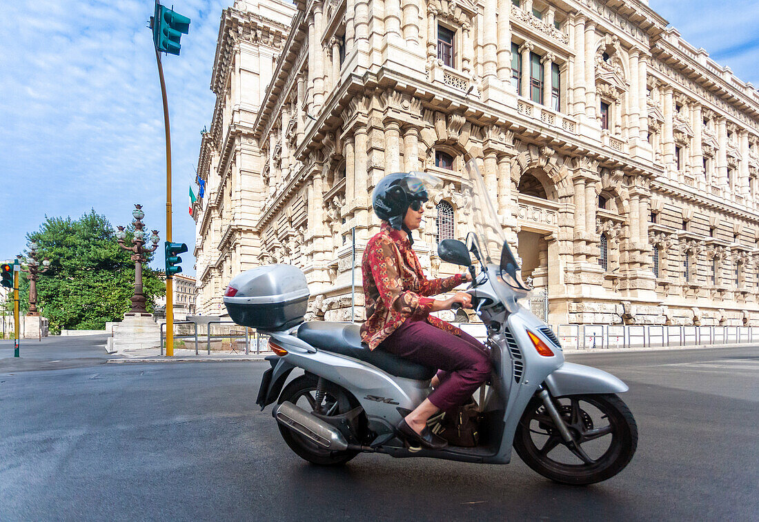 Rome, Italy, July 22 2017, Woman smokes while riding a scooter near The Supreme Court of Cassation.