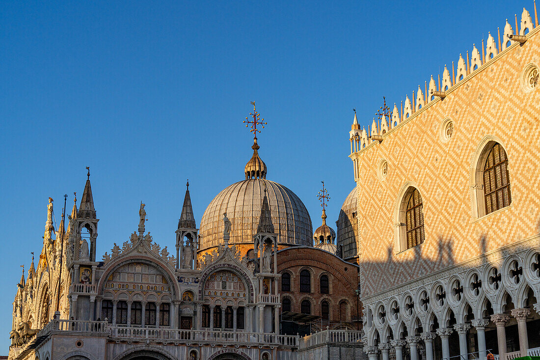 Golden light on the south facade of St. Mark's Basilica with the Doge's Palace at right, in Venice, Italy.