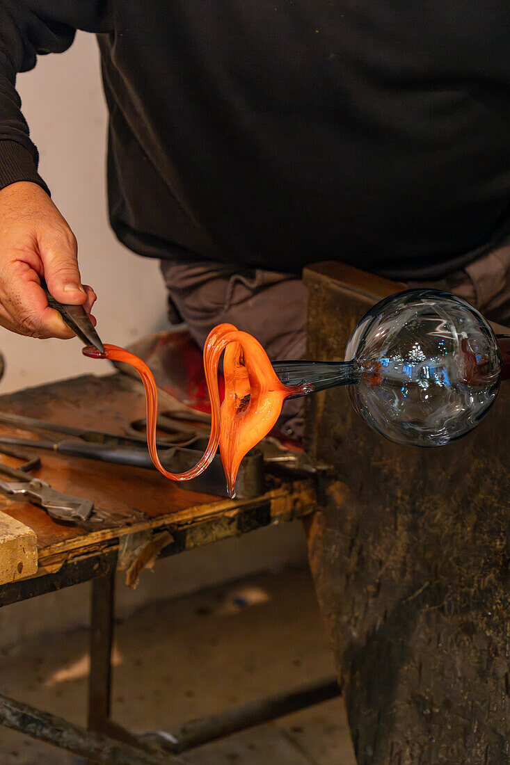 Der Glasbläser spannt das Glas mit Stützen,um einen Henkel zu formen,bei einer Glasbläservorführung in Venedig,Italien.