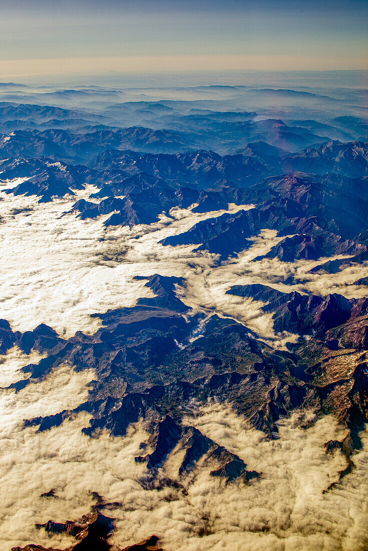 The breathtaking Pyrenees mountains rise above thick clouds, offering a stunning aerial perspective at dawn.