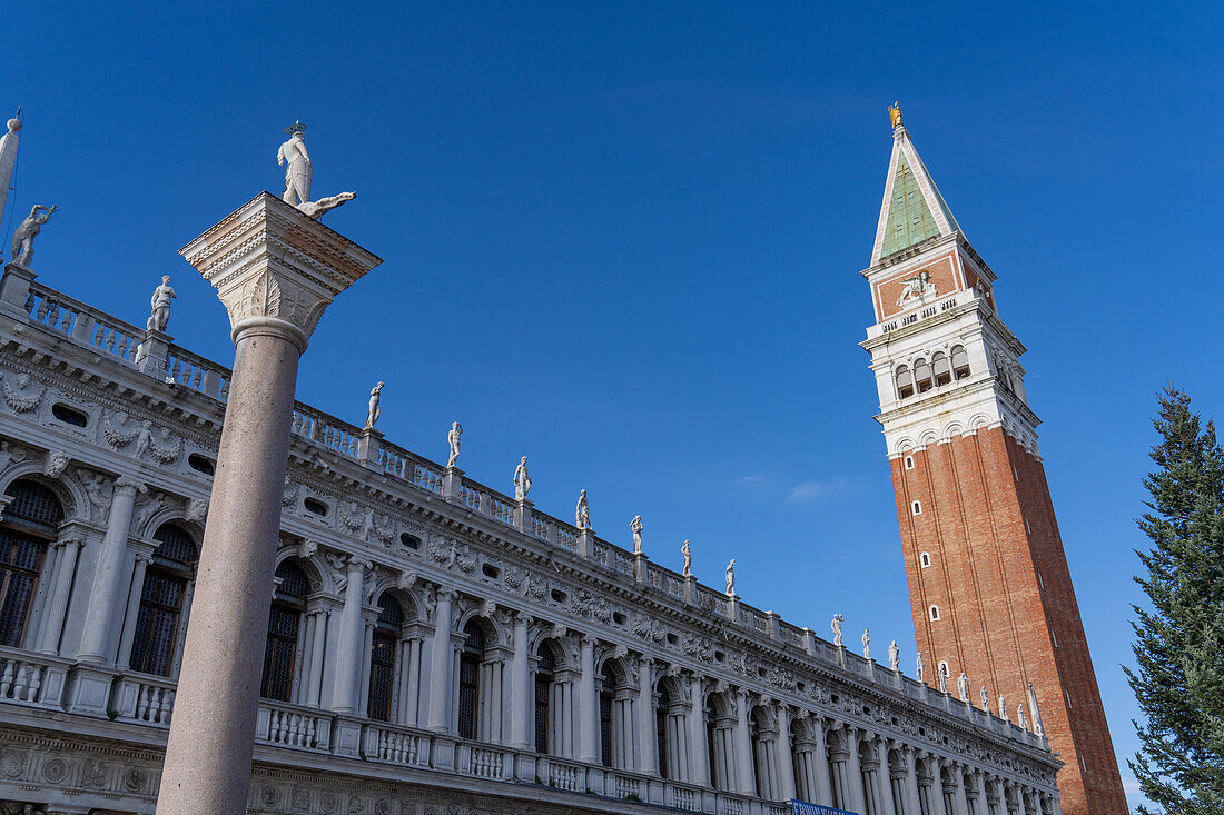 The campanile or bell tower of the Patriarchal Cathedral Basilica of Saint Mark or St. Mark's Basilica in Venice, Italy. At left is the Marciana National Library and the Column of San Todaro.