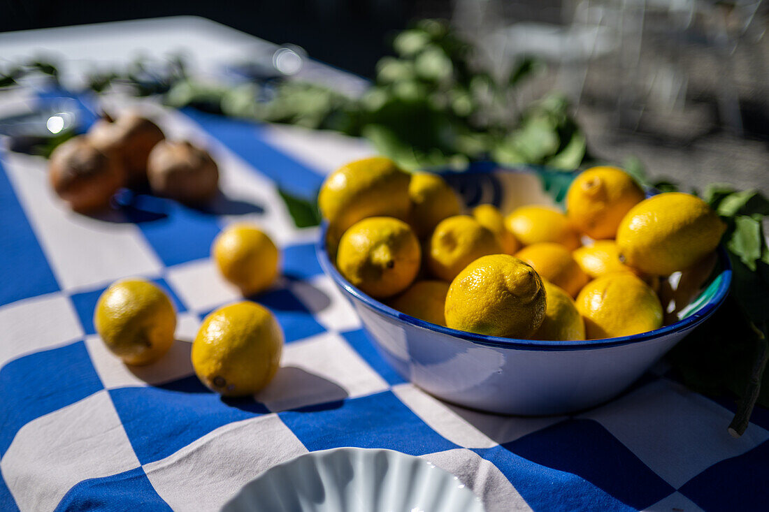 A vibrant display of yellow lemons on a checkered blue tablecloth. Captured at a wedding in Malaga, Spain, evoking a fresh and rustic atmosphere.