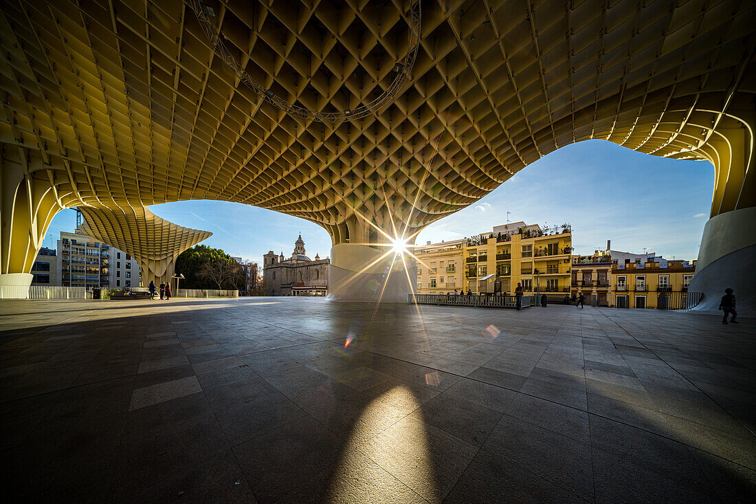 Morgensonne strahlt durch Las Setas Struktur in Sevilla,Spanien,wirft Schatten auf die städtische Landschaft,zeigt architektonische Schönheit und Stadtleben.