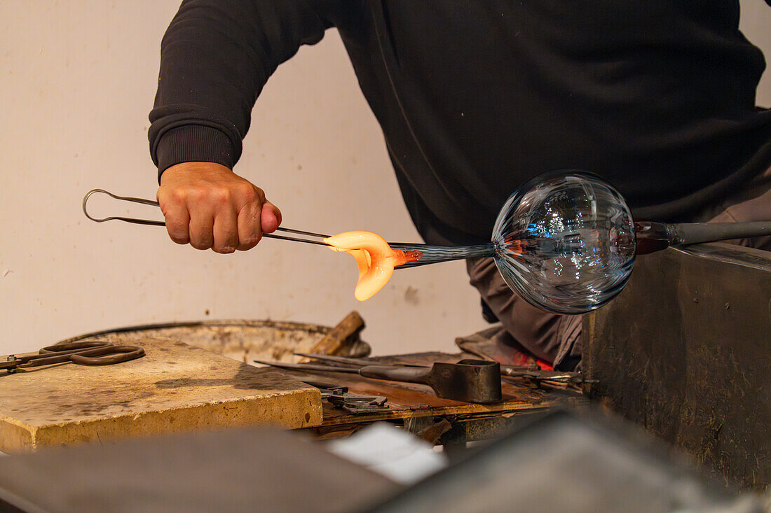 The glassblower shapes a spout for the pitcher with jacks in a glassblowing demonstration in Venice, Italy.