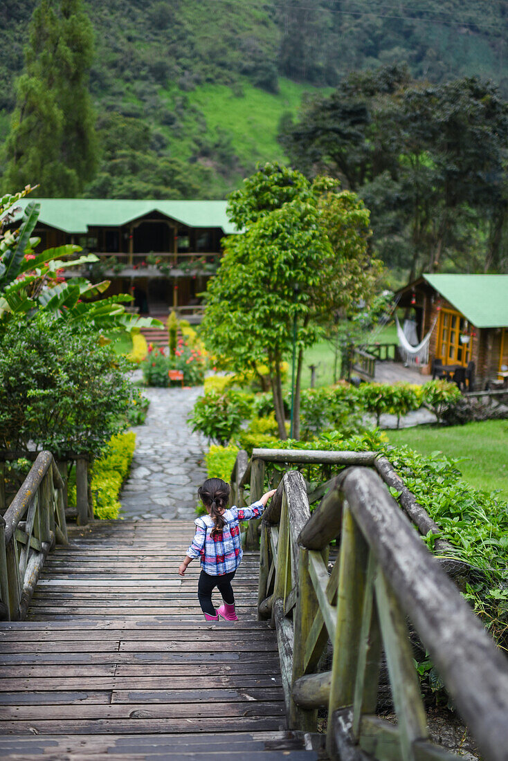 Young girl walking down the wooden stairs of a mountain hotel in Colombia